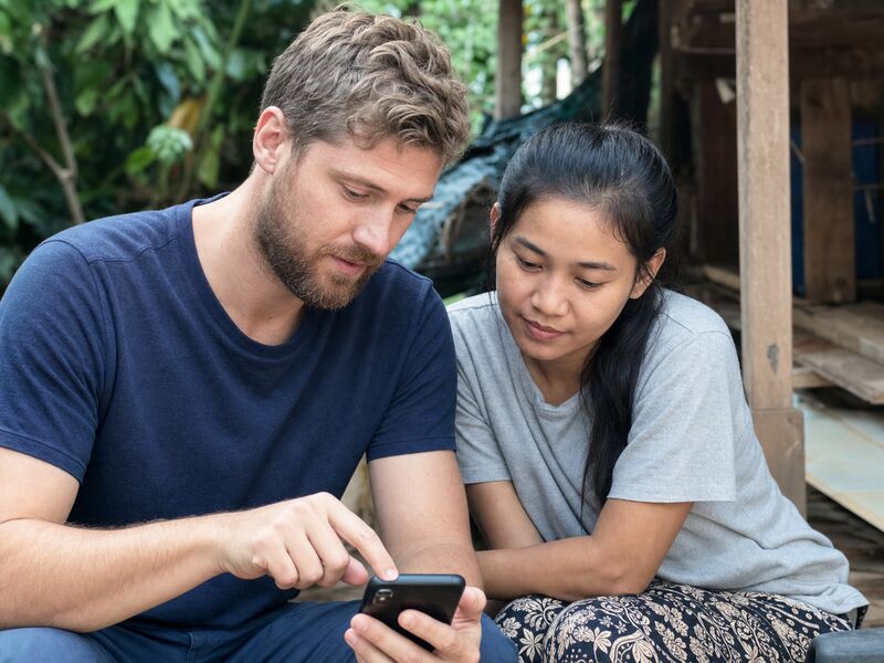 A couple looking together at a phone, appearing to plan something together.
